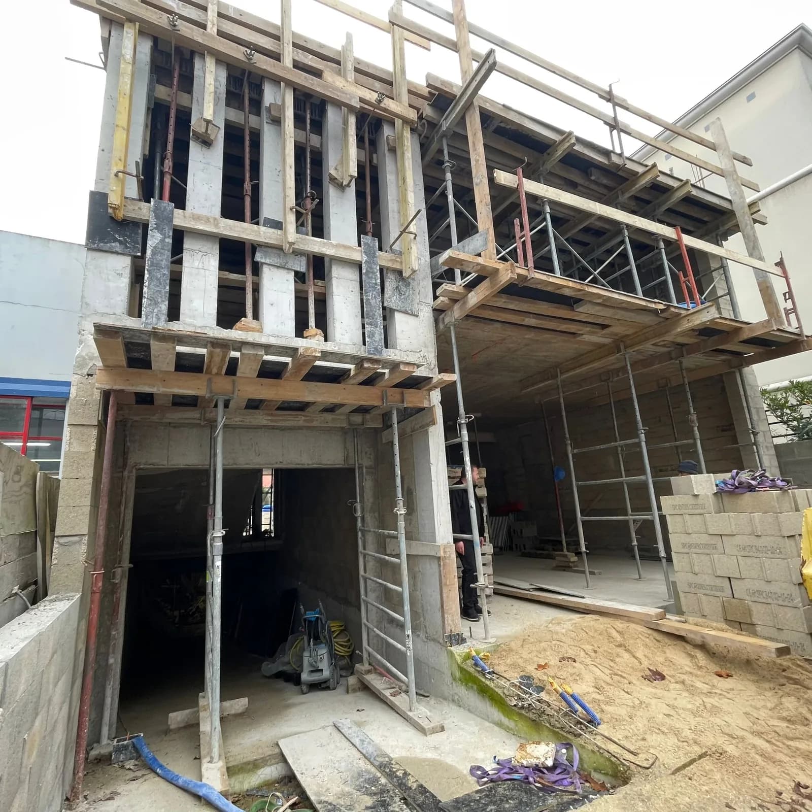 Chantier de gros œuvre : étaiement, coffrage et parpaings d'une extension en cours d'élévation.